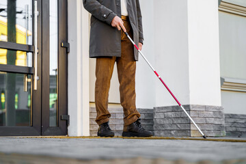 Blind man with a walking stick. Walks on tactile tiles for self-orientation while moving through the streets of the city
