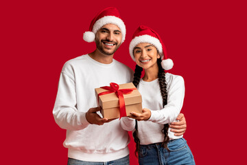 Happy Young Arab Couple Wearing Santa Hats With Gift Box In Hands