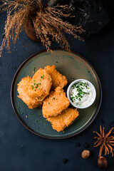 Fried chicken nuggets with sauce and green onions on a plate.