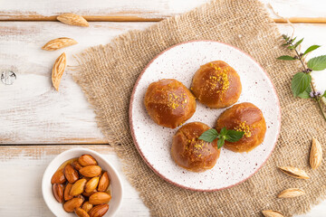 Traditional turkish dessert sekerpare with almonds and honey on white wooden, top view.