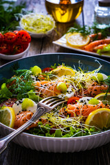 Salmon salad - smoked salmon, goat cheese and fresh vegetables on wooden table
