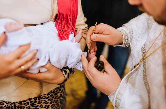 The priest in the church conducts the ceremony, the ritual of anointing the child's feet. Photography, religion.