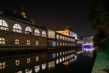 Iconic building of the central market in Ljubljana illuminated at night, the bridge of Preseren sqare in the background
