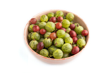 Fresh red and green gooseberry in ceramic bowl isolated on white, side view.