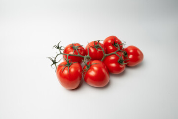 A bunch of red juicy tomatoes lie straight with the tops