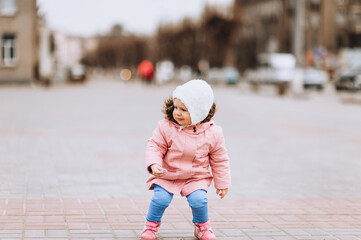 A little girl, a child of preschool age, walks in the city and draws on asphalt, tiles with multi-colored chalk. Photography, childhood.