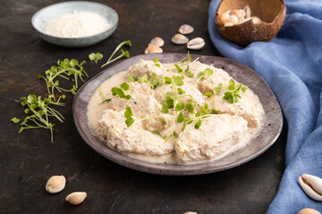 Stewed chicken fillets with coconut milk sauce and rucola microgreen. side view, close up.