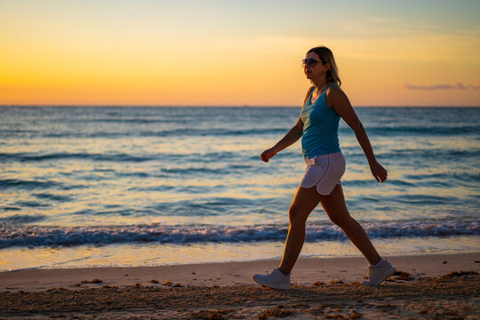 Woman walking on sunny, tropical beach at daybreak
