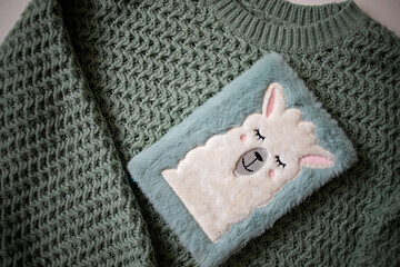 Warm olive-colored knitted sweater. A fluffy notebook. Texture of knitting. Winter warm clothes.