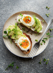 Bread toast, boiled eggs, avocado slice, microgreens on a plate