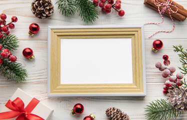 Fototapeta premium Photo frame, decorations, fir tree branches on white wooden background