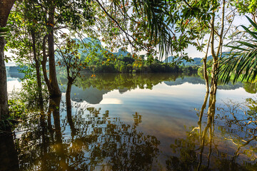 Fototapeta premium Blurred panoramic nature background on the large lake, reflected by the water of trees, the atmosphere is surrounded by big mountains