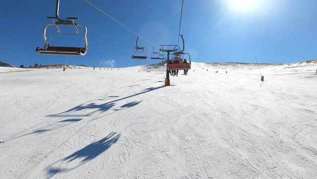 View going up from ski chairlift over snowy slopes in ski resort in a sunny day