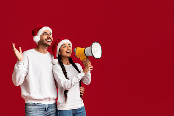 Christmas Ad. Middle Eastern Couple In Santa Hats Making Announcement With Megaphone