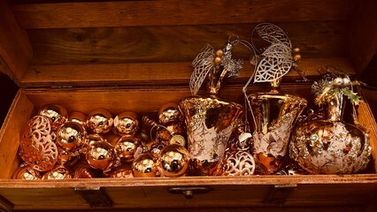 Golden decorations of Christmas tree of different shapes in wooden chest. New year concept.
