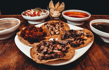 mexican tacos on plates and wooden table with different hot sauces