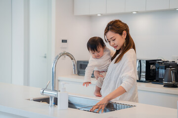 赤ちゃんを抱っこしながら家事をするお母さん © maroke