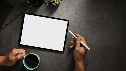 Top view office desk with hands holding digital tablet, empty screen tablet for your present