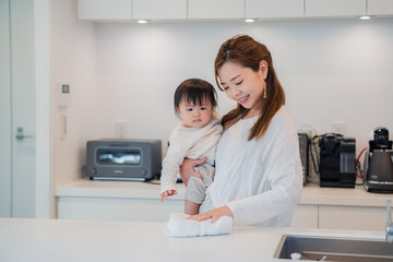 赤ちゃんを抱っこしながら家事をするお母さん © maroke