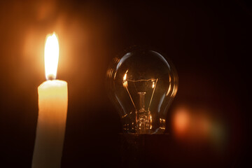 burning candle with bulb on black background
