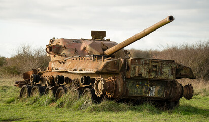an abandoned rusting British FV4201 Chieftain main battle tank wreck in afternoon sunlight 