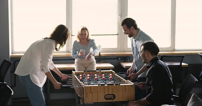 Smiling friends workmates playing table football game, winning, screaming, celebrate victory, feel happy, enjoy table soccer in office during break time to relieve stress from work. Friendship, hobby