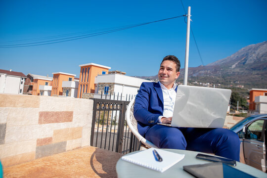 Adult businessman using laptop and phone