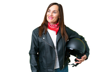 Middle age caucasian woman with a motorcycle helmet over isolated chroma key background looking to the side and smiling