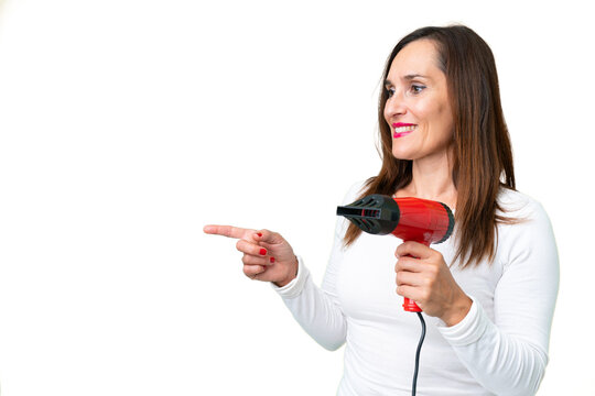 Middle age woman holding a hairdryer over isolated chroma key background pointing to the side to present a product