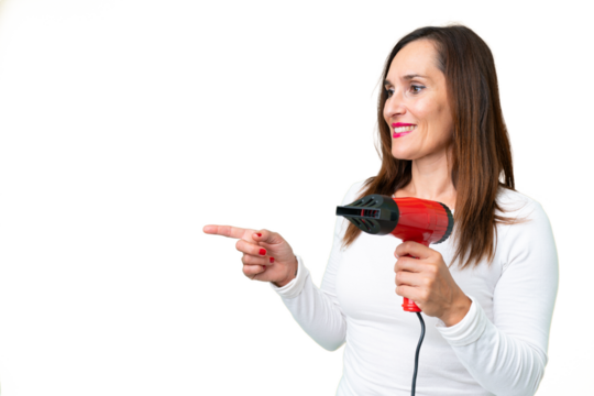Middle age woman holding a hairdryer over isolated chroma key background pointing to the side to present a product