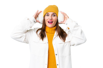 Middle age woman wearing winter muffs over isolated chroma key background with surprise expression