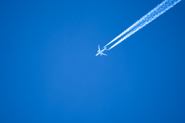 high altitude twin engine contrails (jet airplane vapour trails) across a deep blue clear sky