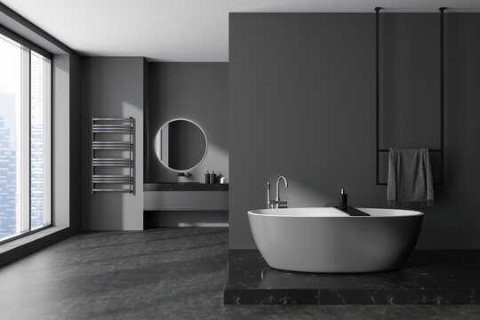 Grey bathroom interior with tub and sink near panoramic window. Copy space