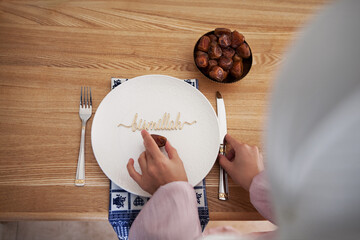 Muslim woman serves table with cutlery and plate of dates fruit with inscription text bismillah