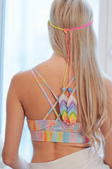 Portrait of blonde girl from the back in colorful hippie top with bohemian accessories