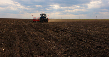 Fototapeta premium Agriculture Farm Tractor Seeding Machine Field Seeder Village Planter Rural Working Combine Tillage Plowing Agricultural Equipment Season Sowing Grain Spring time Process Planting Seeds 