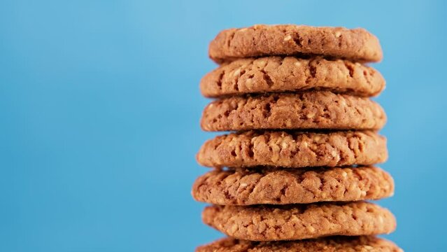Stack of tasty cookies rotating on blue background. Homemade food concept with copy space. Rotating fresh cookies. Tasty bakery dessert. Healthy food. Close-up in 4K, UHD