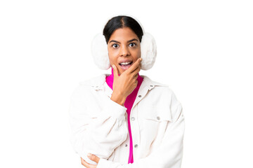 Young African American woman wearing winter muffs over isolated chroma key background surprised and shocked while looking right