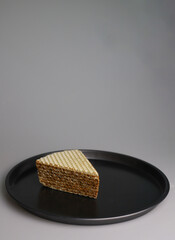sweet waffle triangular piece of cake soaked in boiled condensed milk on a black round kitchen tray. for flyers banners signage labels