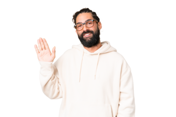 Young man with beard over isolated chroma key background saluting with hand with happy expression