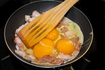 Scrambled eggs with bacon in a pan.