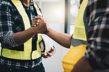 Fototapeta na wymiar Architect and engineer construction workers shaking hands while working for teamwork and cooperation concept after finish an agreement in the office construction site, success collaboration concept