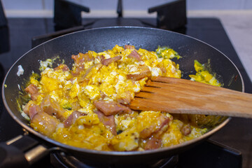 Scrambled eggs with bacon in a pan.