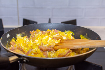 Scrambled eggs with bacon in a pan.