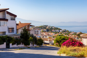 Fototapeta na wymiar Street in Residential Neighborhood with homes and flowers overlooking Aegean Sea. Kusadasi, Turkey. Sunny Morning.