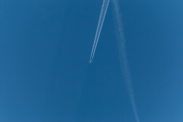 The plane flies through the clear blue sky leaving long trails of steam. With copy space to add...
