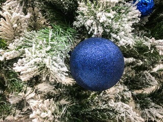 Blue shiny Christmas ball on the tree. Close-up. Festive Christmas toys. Christmas decorations. Christmas and New Year. Christmas mood.