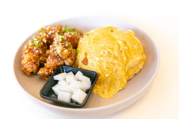 Creamy omelet on rice with fried chicken.