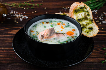 Fish soup with salmon, cream, potatoes, dill and bread with sauce and spices.