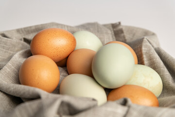 Closeup of soft brown and green chicken eggs wrapped in a towel